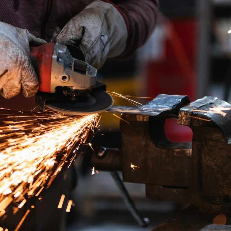 Craftsman grinding metal with grinder in vice
