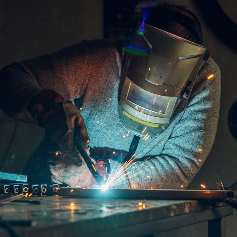Man worker welding metal with welding machine in a factory or workshop